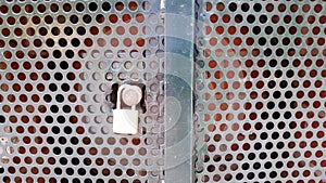 Padlocked metal cupboard with round cutout holes.