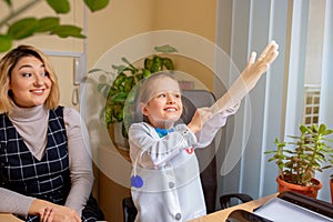 Paediatrician doctor examining a child in comfortabe medical office. Little girl playing pretends like doctor for woman