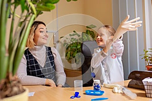 Paediatrician doctor examining a child in comfortabe medical office. Little girl playing pretends like doctor for woman