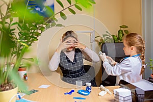 Paediatrician doctor examining a child in comfortabe medical office. Little girl playing pretends like doctor for woman