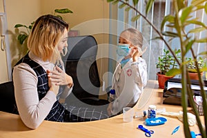 Paediatrician doctor examining a child in comfortabe medical office. Little girl playing pretends like doctor for woman
