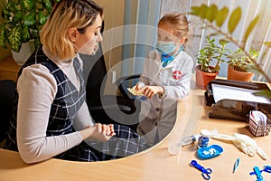 Paediatrician doctor examining a child in comfortabe medical office. Little girl playing pretends like doctor for woman