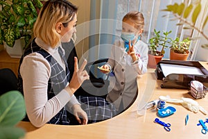 Paediatrician doctor examining a child in comfortabe medical office. Little girl playing pretends like doctor for woman