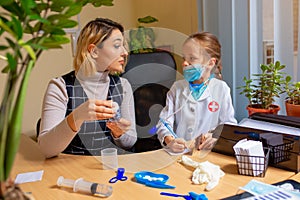 Paediatrician doctor examining a child in comfortabe medical office. Little girl playing pretends like doctor for woman