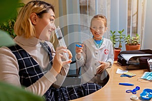 Paediatrician doctor examining a child in comfortabe medical office. Little girl playing pretends like doctor for woman