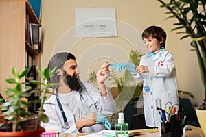 Paediatrician doctor examining a child while wearing face mask in comfortabe medical office
