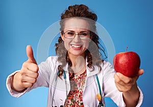 Paediatrician doctor giving an apple and showing thumbs up