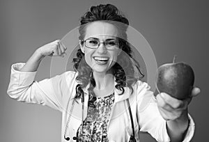 Paediatrist woman giving an apple and showing biceps on