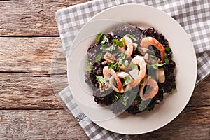 Paella from black rice with seafood close-up on a plate. horizon