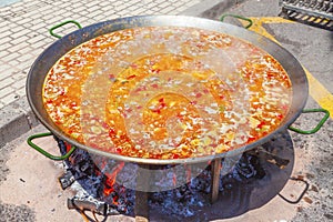 Paella from chicken, vegetables and rice. The national Spanish dish of paella in a large skillet is cooked on an open fire, at the