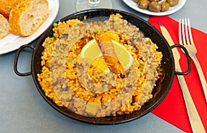 Paella marinera with lemon on iron frypan