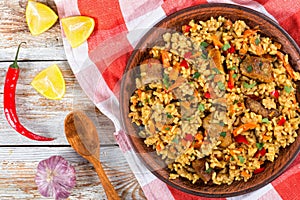 Paella with meat, pepper, vegetables and spices on clay dish