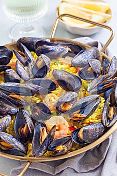 Paella with mussels and shrimps in traditional plate, vertical, closeup