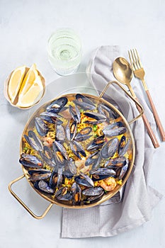 Paella with mussels and shrimps in traditional plate, vertical, top view