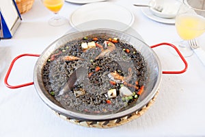 Paella negra on the pan, white table photo