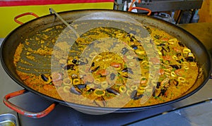 Paella with seafood in a huge pan close-up on street food market. Spanish traditional dish