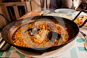 Paella, the traditional dish in Spain. Rustic cast iron skilled filled with seafood paella. Rice with prawns, mussels