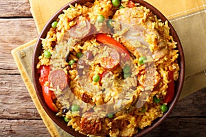 Paella Valenciana with meat, sausage chorizo, vegetables and spices close-up in a bowl. Horizontal top view