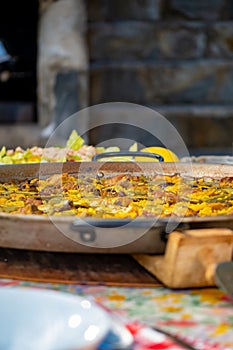 Paellera handle with a freshly cooked authentic Valencian paella, to serve on a table with the dishes set photo