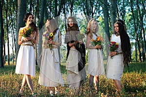 Pagan women in the forest holding flowers