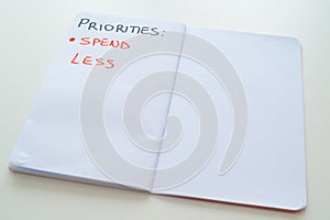 Notebook page, with text `priorities: spend less` photo