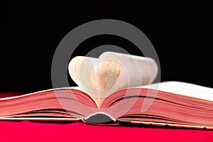 The pages of the book are folded in the shape of a heart on a pink and black background, place for text