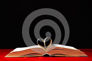 The pages of the book are folded in the shape of a heart on a red and black background, place for text