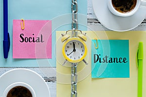 Pages separated by a chain with the words `Social Distance` Clock, office items. The concept of limiting mutual closeness both at