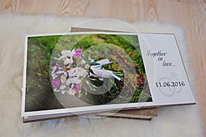 Pages of wedding photobook or wedding album at carpet on wooden