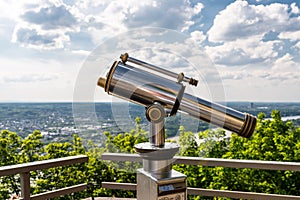 Paid single lens telescope, set on a high vantage point with a view of the city.