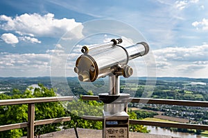 Paid single lens telescope, set on a high vantage point with a view of the city.