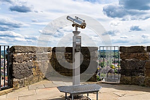 Paid single lens telescope, set on a high vantage point with a view of the city.