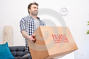 Pain in back. Young man suffering while lifting a cardboard box