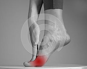 Pain in ball of foot. Woman holding leg with red spot closeup. Ache in metatarsal heads. Intense physical activity photo