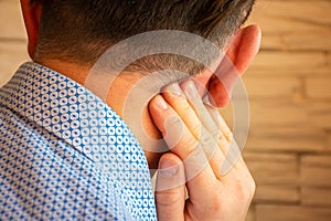 Pain behind ear in area of mastoid process concept photo. Person holds his hand over area behind ear, where pain is suspected due