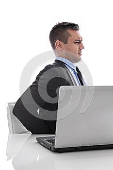 Pain: businessman sitting with backache at desk isolated on whit