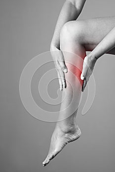 Pain in the calf muscle of the woman. Massage of female feet. Pain in the human body on a gray background