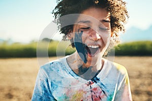 The pain can exploded. Shot of a teenage boy having fun with colourful powder at summer camp.