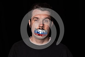 Pain. Conceptual portrait of young man with three colors duct tape over his mouth isolated on dark background
