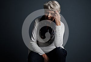 Pain does come with age sometimes. Studio shot of a stressed out elderly woman sitting down with her eyes closed and