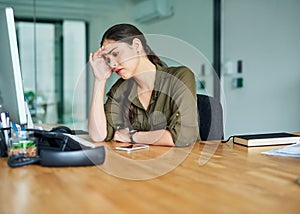 This pain is far too intense. Shot of a young businesswoman suffering with a headache in an office.