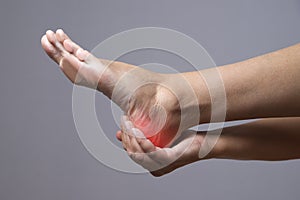 Pain in the foot. Massage of female feet. Pain in the human body on a gray background