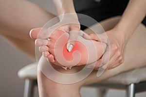 Pain in the foot of a woman. Highlighted in red. On a gray background. Close up