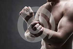 Pain in the hand. Muscular male body. Handsome bodybuilder posing on gray background. Low key close up studio shot photo