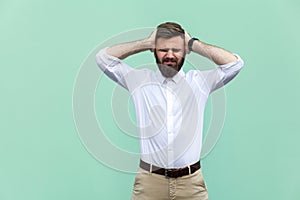 Pain in head. Pained businessman, has a headache, isolated on light green background.