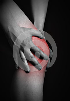 Pain in the knee. Chiropractor doing massage in sick knee in red