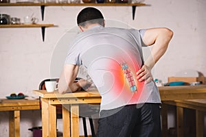 Pain in the spine, a man with backache at home, injury in the lower back