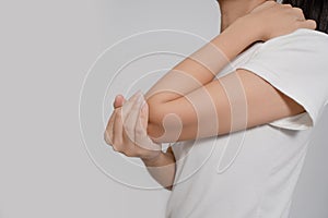 Pain in a waman`s body. Asian woman has elbow pain. Sheis holding hand to spot of elbow pain indicating location of the pain