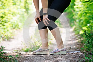 Pain in woman`s knee, massage of female leg, injury while running, trauma during workout