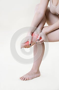 Pain in woman`s legs, massage of female feet on beige background